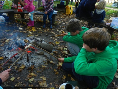 Children toasting marshmallows over a fire pit.